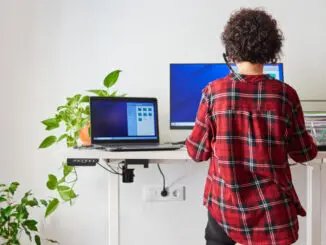 Eine Frau arbeitet am Laptop an einem höhenverstellbaren Schreibtisch